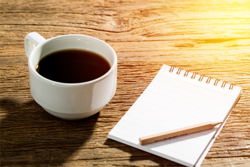 image of a cup of coffee and a notepad and pencil